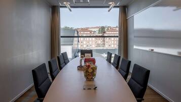 Un salón de conferencias con una larga mesa, sillas y una cesta decorativa de frutas.