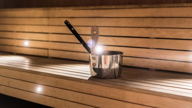 A stainless steel pot with a wooden handle on a wooden bench. - Scandic Alvik (Bromma)