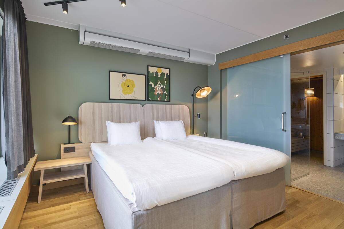 Une chambre moderne avec un grand lit, une table de chevet, une lampe et un climatiseur fixé au mur.