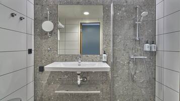 Een moderne badkamer met een rechthoekig wastafelmeubel, een spiegel, een handdouche en een toilet.