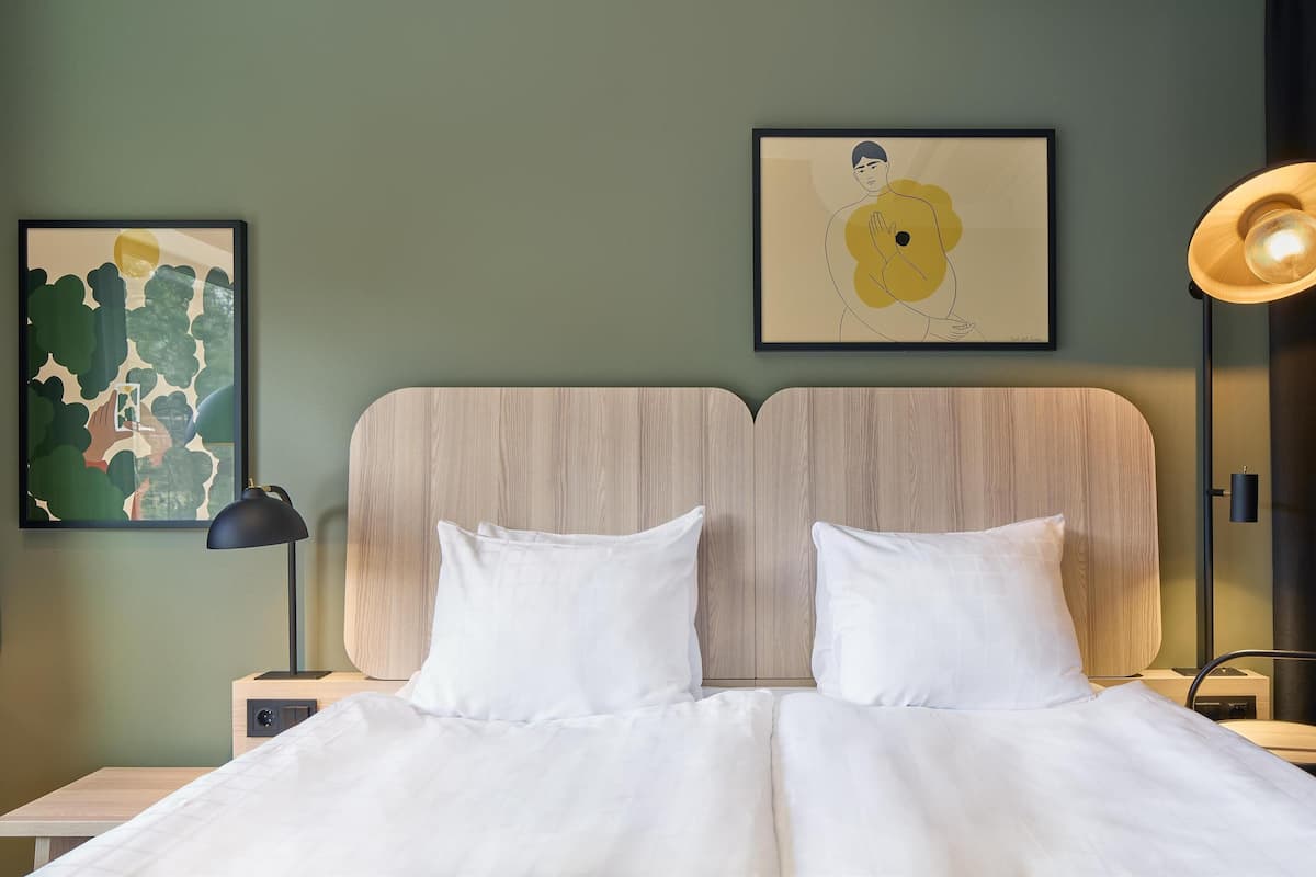 Un lit bien fait, avec du linge de lit blanc, une tête de lit en bois et deux tables de chevet avec des lampes.