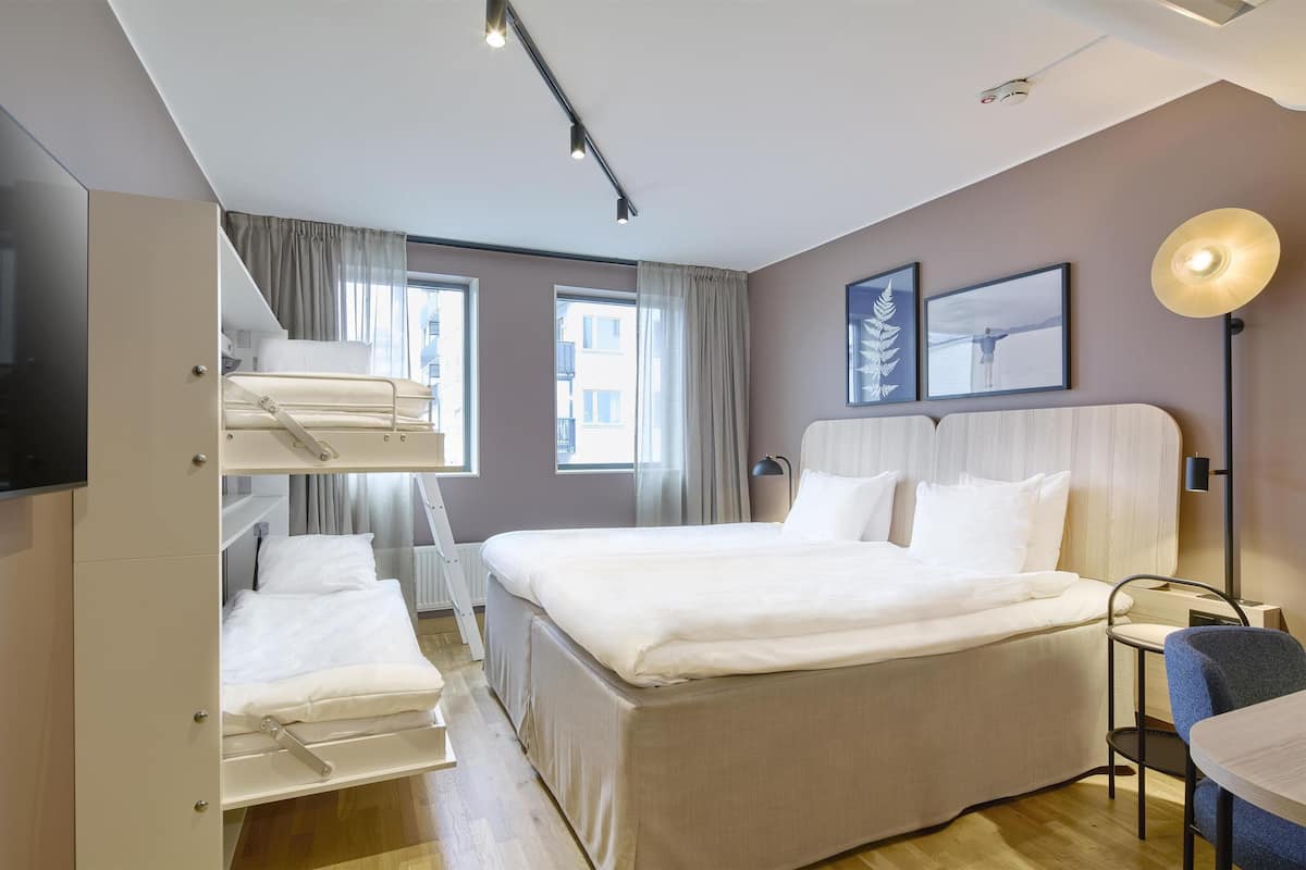 Une chambre d’hôtel avec un grand lit, un bureau, une chaise, une télévision et une fenêtre avec des rideaux.