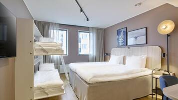 Habitación de hotel con una cama grande, un escritorio, una silla, un televisor y una ventana con cortinas.