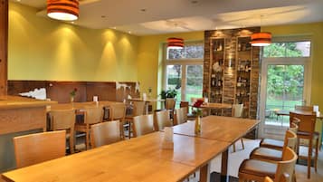 Un restaurante con mesas y sillas de madera, un muro de acento de piedra y vistas a zonas verdes.
