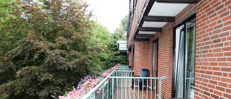 A balcony with a wooden floor, a metal railing, and a table.
