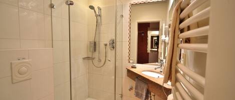 Une salle de bain moderne dotée d’une douche à parois de verre, d’un lavabo avec un porte-serviettes et d’un miroir encadré.