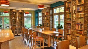Un comedor espacioso con una larga mesa de madera y sillas, rodeado de estanterías llenas de libros.