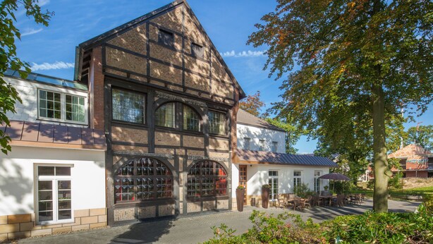 Un edificio tradicional de entramado de madera con ventanas grandes y fachada blanca.