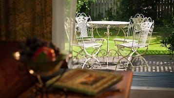 Un patio con una mesa redonda y cuatro sillas, un frutero y un libro sobre la mesa.