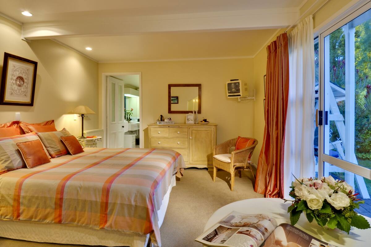 Een slaapkamer met een bed, een kaptafel, een stoel en een raam met gordijnen.