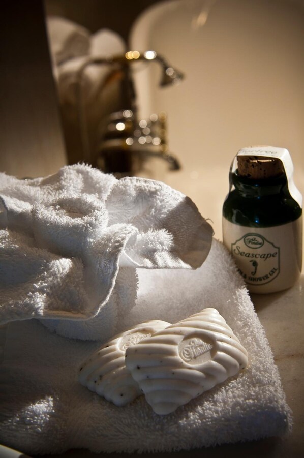 A white towel with a decorative heart and a bottle of Seascape bath salts on a wooden surface. - The Peppertree Luxury Accommodation (Riverlands)