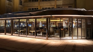Een restaurant met een overdekt terras, glazen wanden en een betegelde vloer.