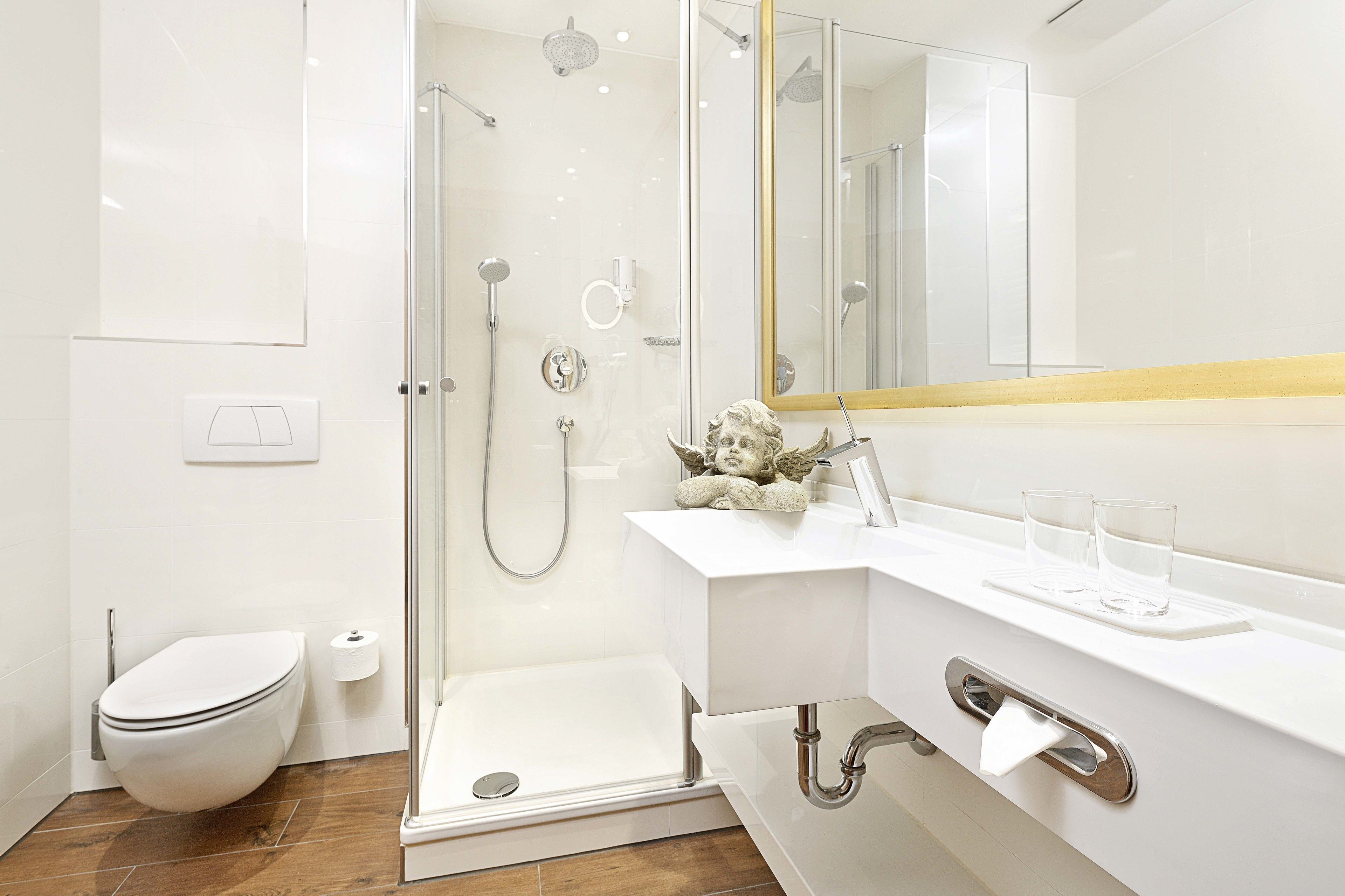 Een moderne badkamer met een douchecabine van glas, een wit toilet en een wastafel met spiegel.