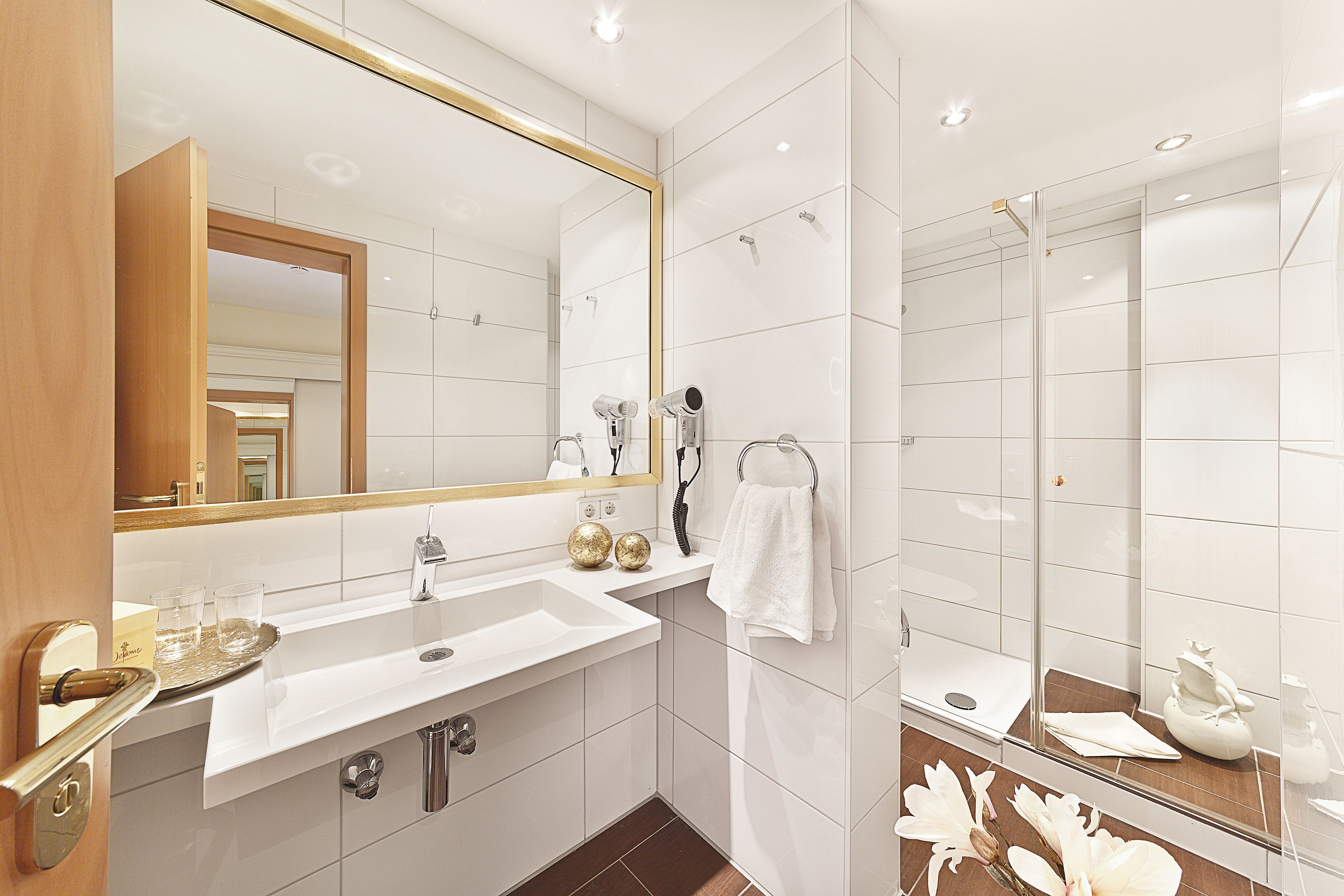 A modern bathroom with a white sink, mirror, and shower.