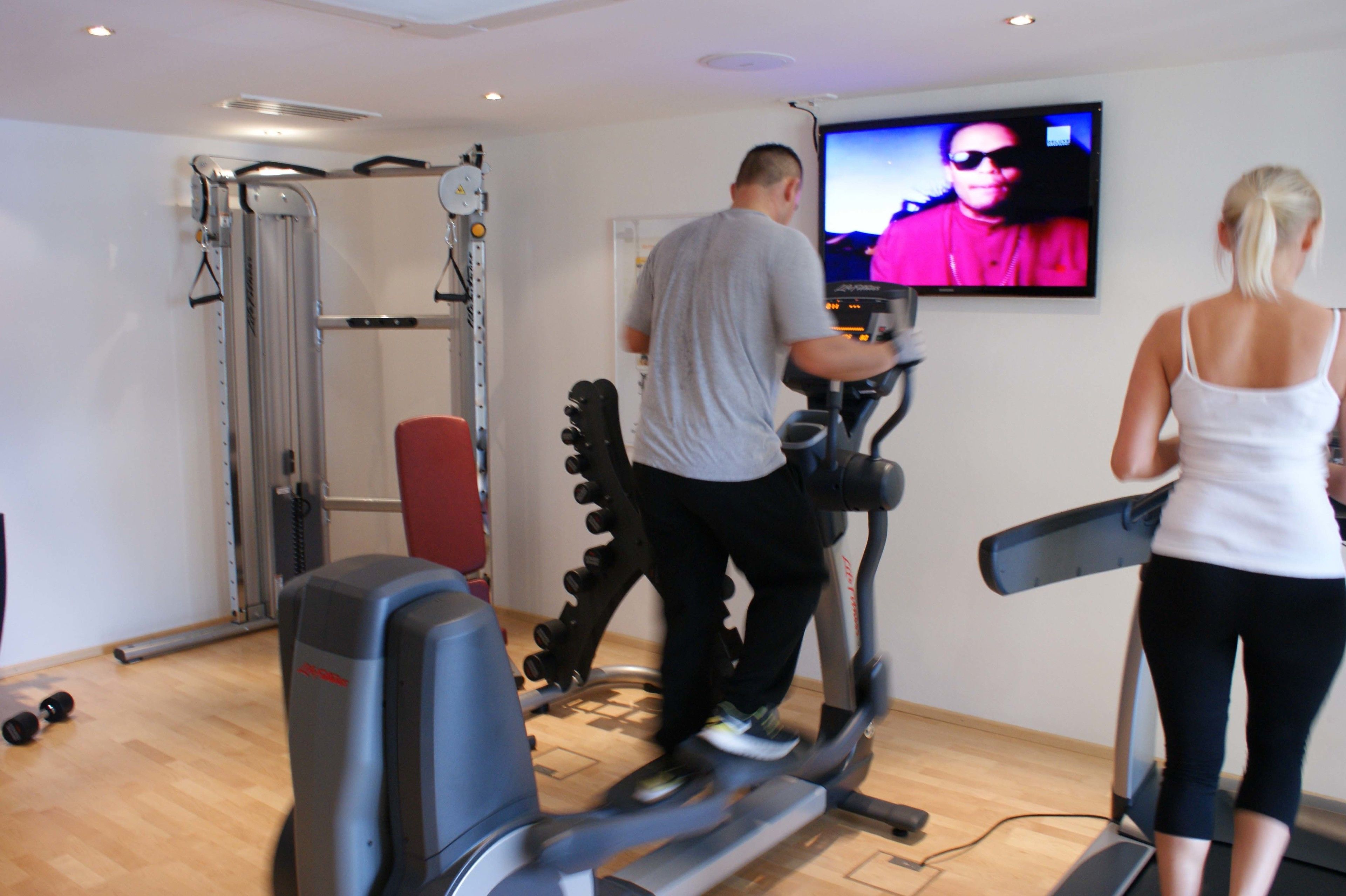 A home gym with exercise equipment including a treadmill, a stationary bike, and a weight machine.