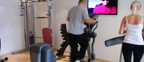 A home gym with exercise equipment including a treadmill, a stationary bike, and a weight machine.