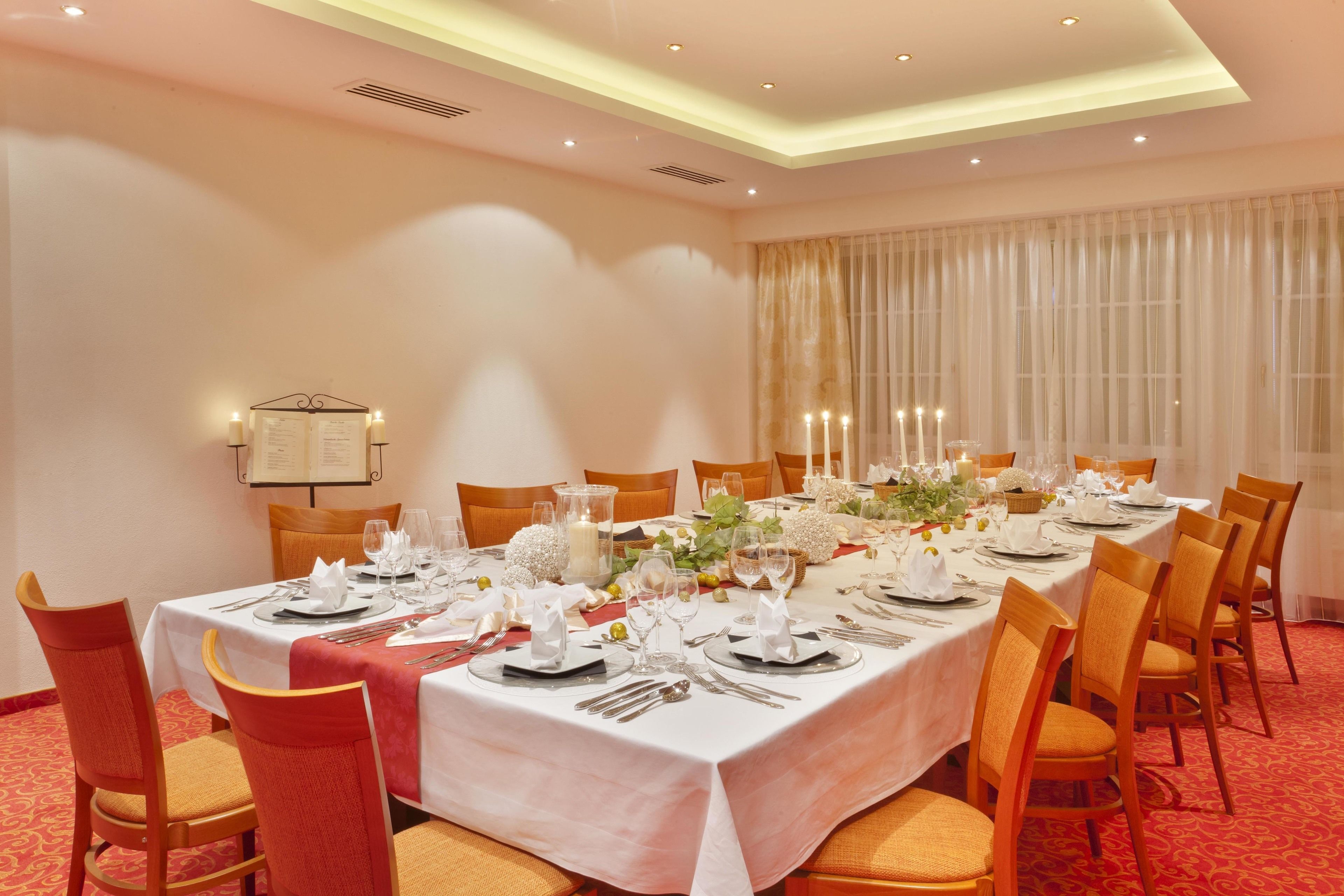 A dining room with a long table set for a meal, surrounded by chairs.