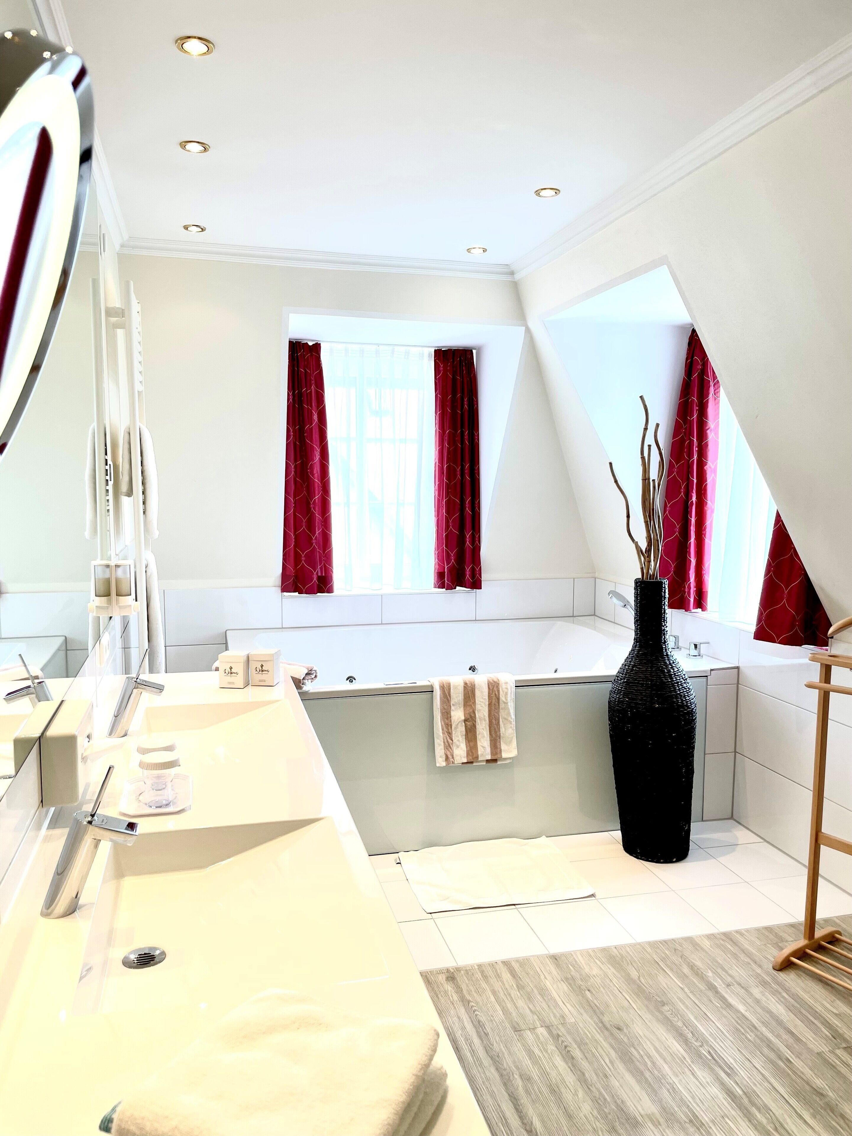 Un baño moderno con un espejo grande, una bañera y un tocador con lavamanos.