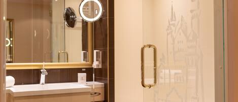 A modern bathroom with a glass shower enclosure, a vanity with a mirror, and a decorative wall.
