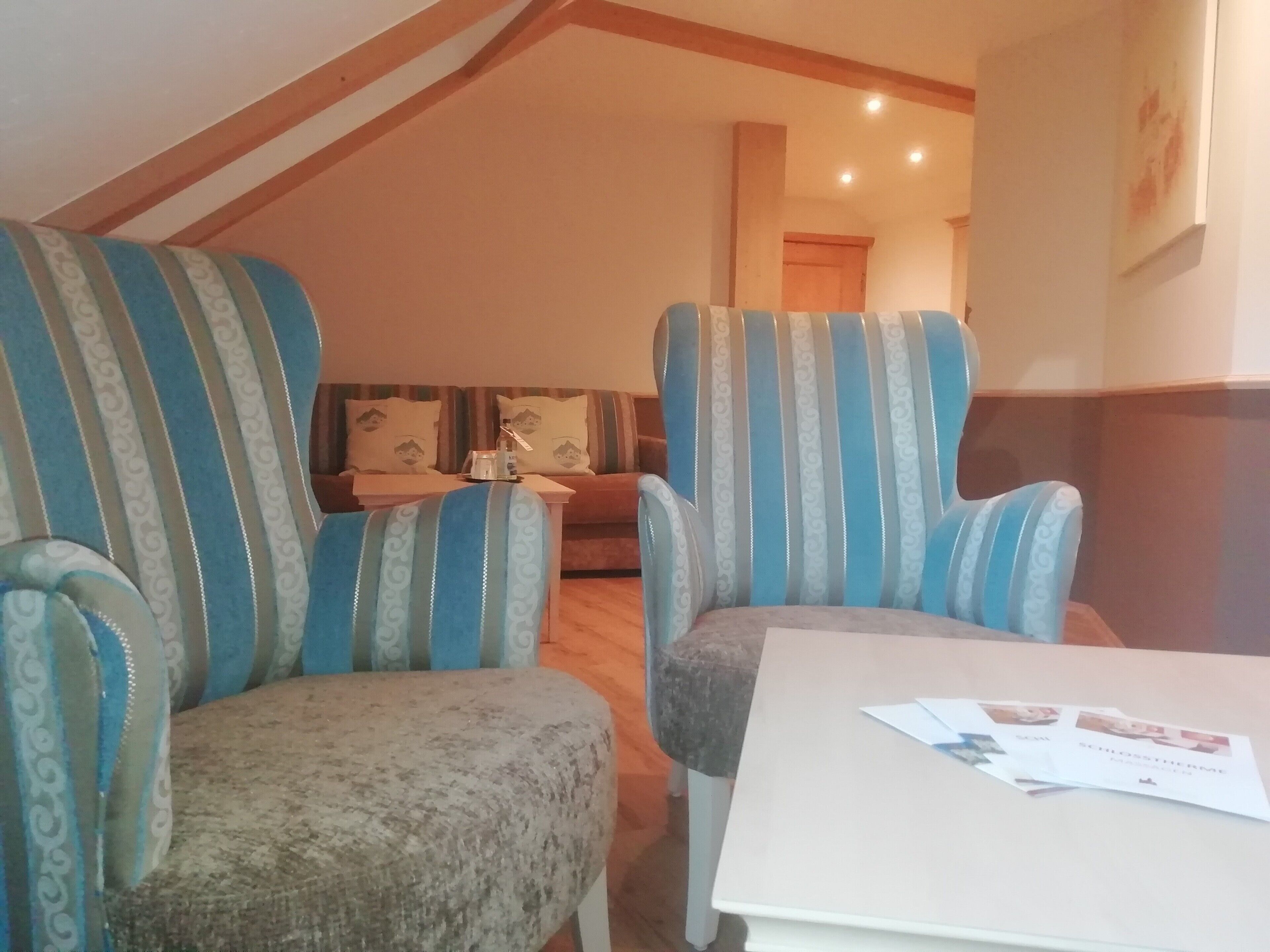 Una sala de estar acogedora con dos sillones a rayas, un sofá y una mesita con papeles.