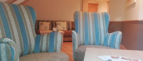 A cozy living room with two striped armchairs, a sofa, and a small table with papers.
