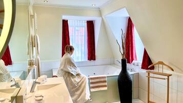 Un baño moderno con una bañera grande, un tocador con varios lavamanos y un espejo.