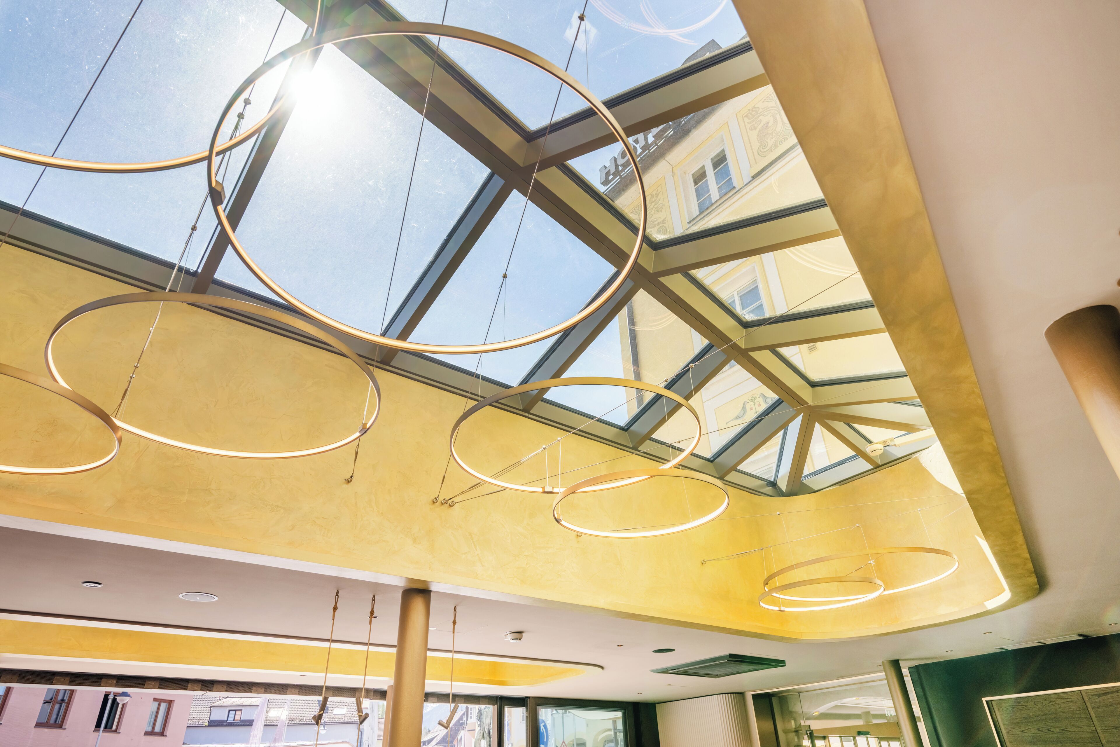 A modern interior with a glass ceiling, circular light fixtures, and a view of buildings outside.