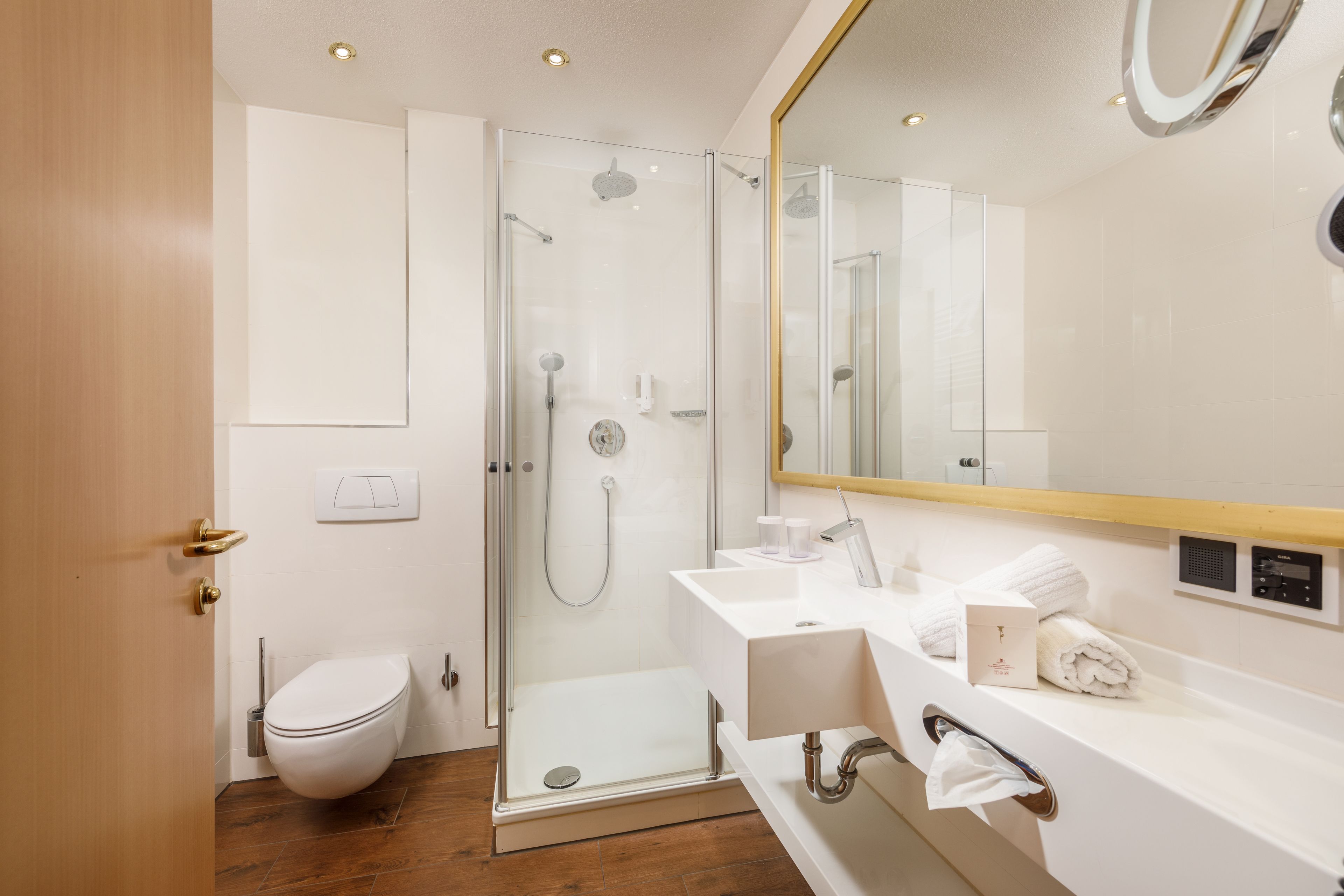 A modern bathroom with a glass-enclosed shower, a white sink, and a large mirror.