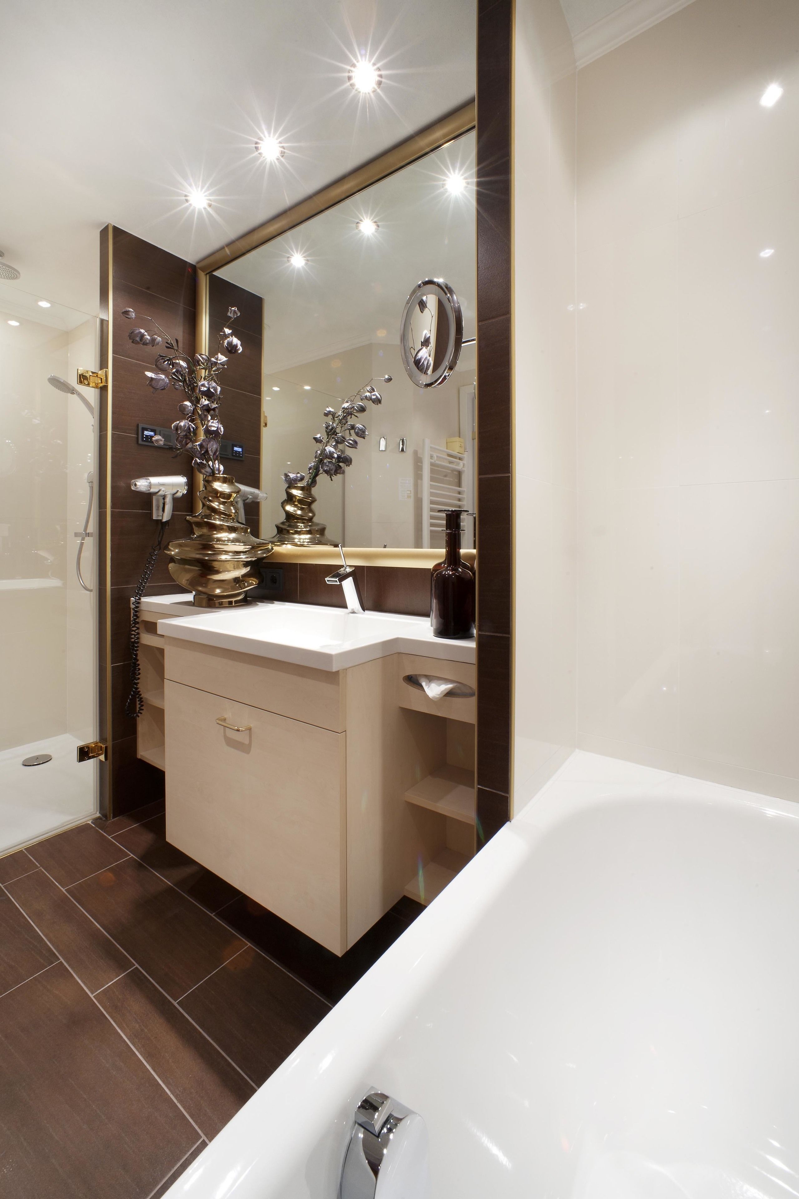 A modern bathroom with a large mirror, a bathtub, and a vanity with a sink.