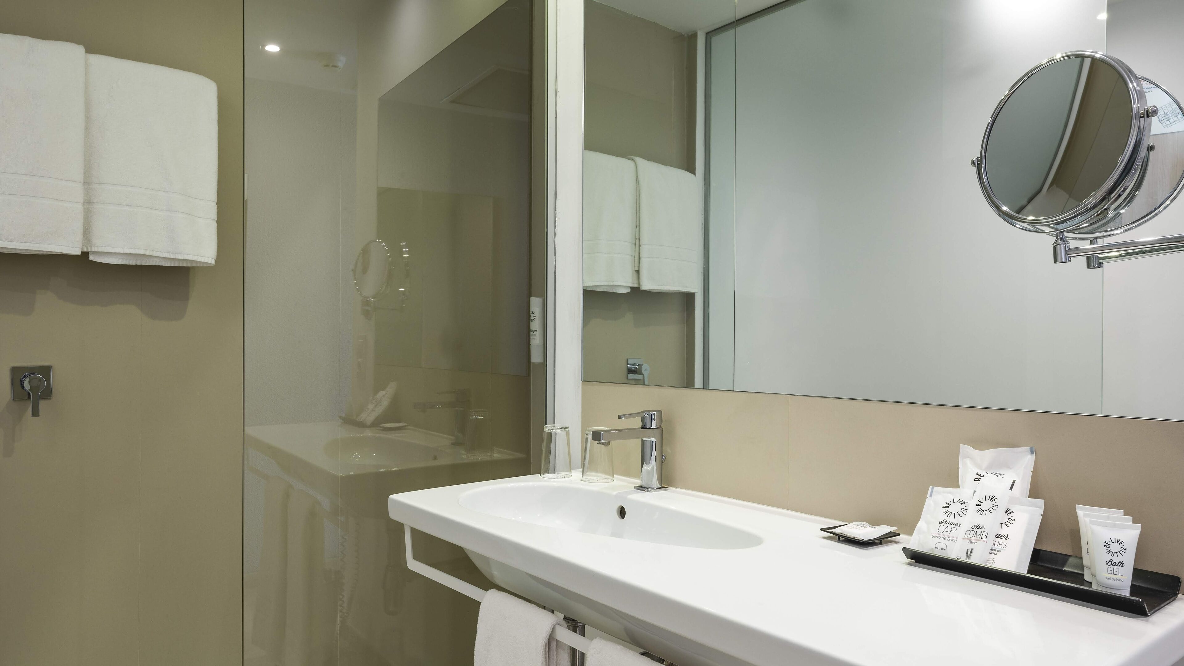 A modern bathroom with a white sink, a large mirror, and a glass shower enclosure.