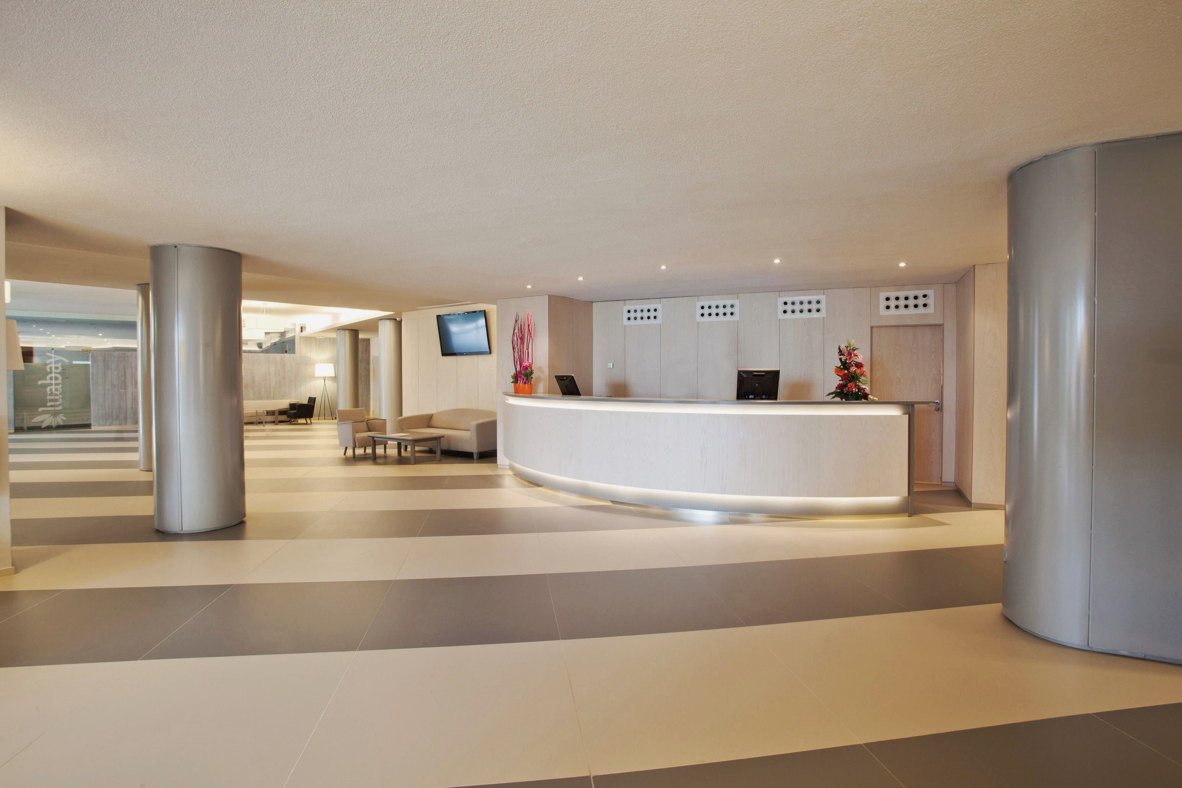 A modern reception area with a curved desk, seating, and a large pillar.