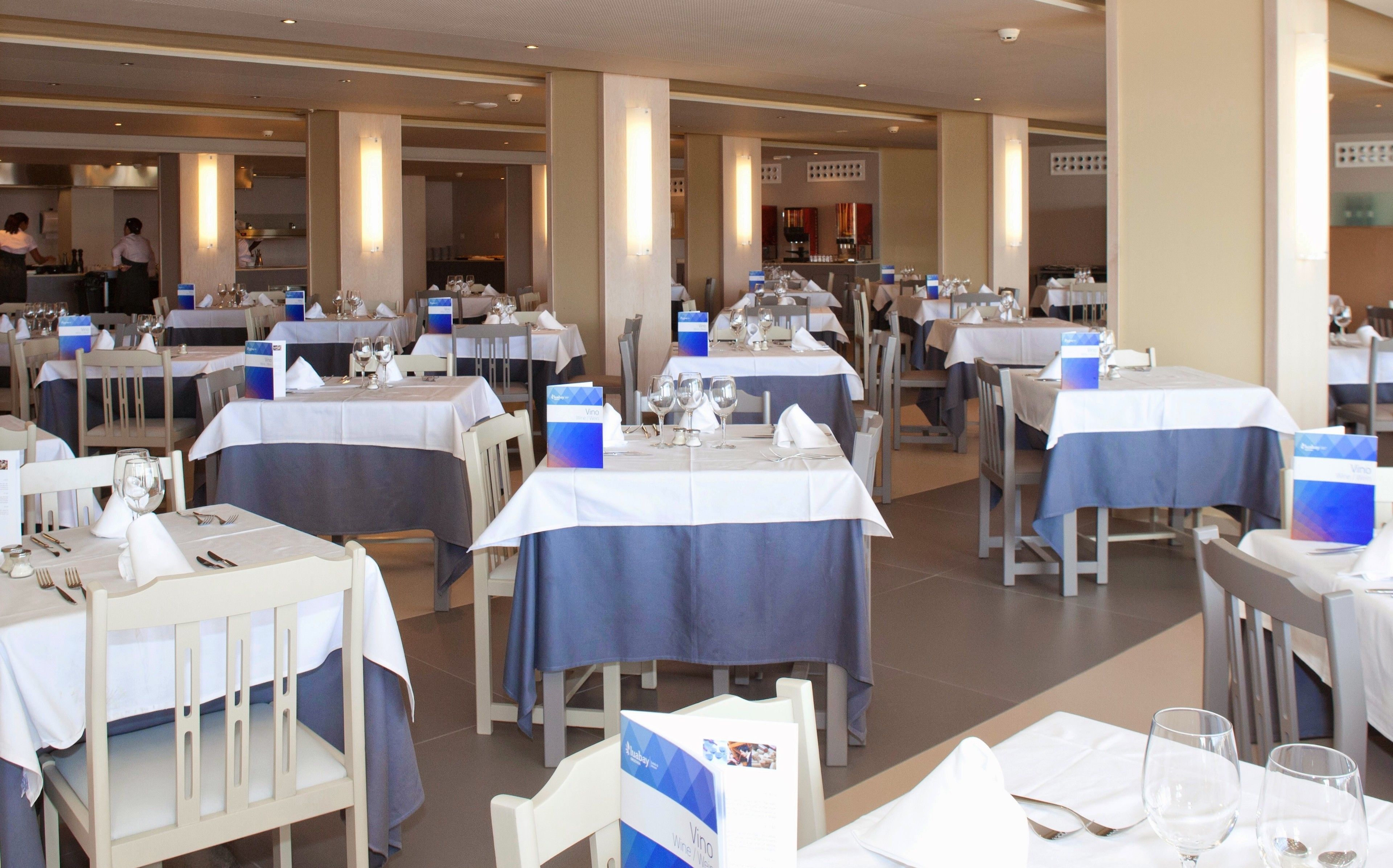 A restaurant with tables set for dining, featuring blue tablecloths and white napkins.
