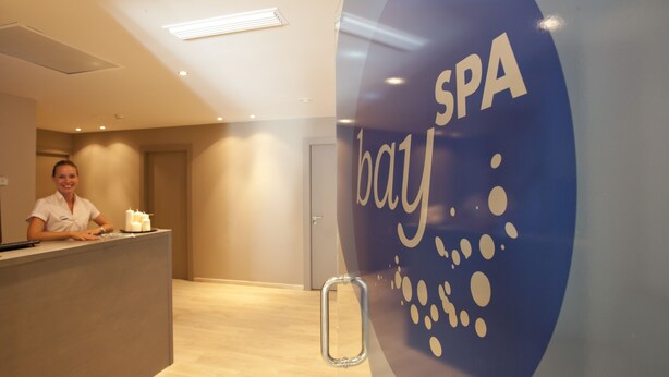 Una mesa de recepción con el logotipo de 'SPA bay' y una persona sentada detrás.