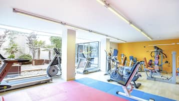 Un gimnasio con cintas de correr, bicicletas estáticas y máquinas de pesas.
