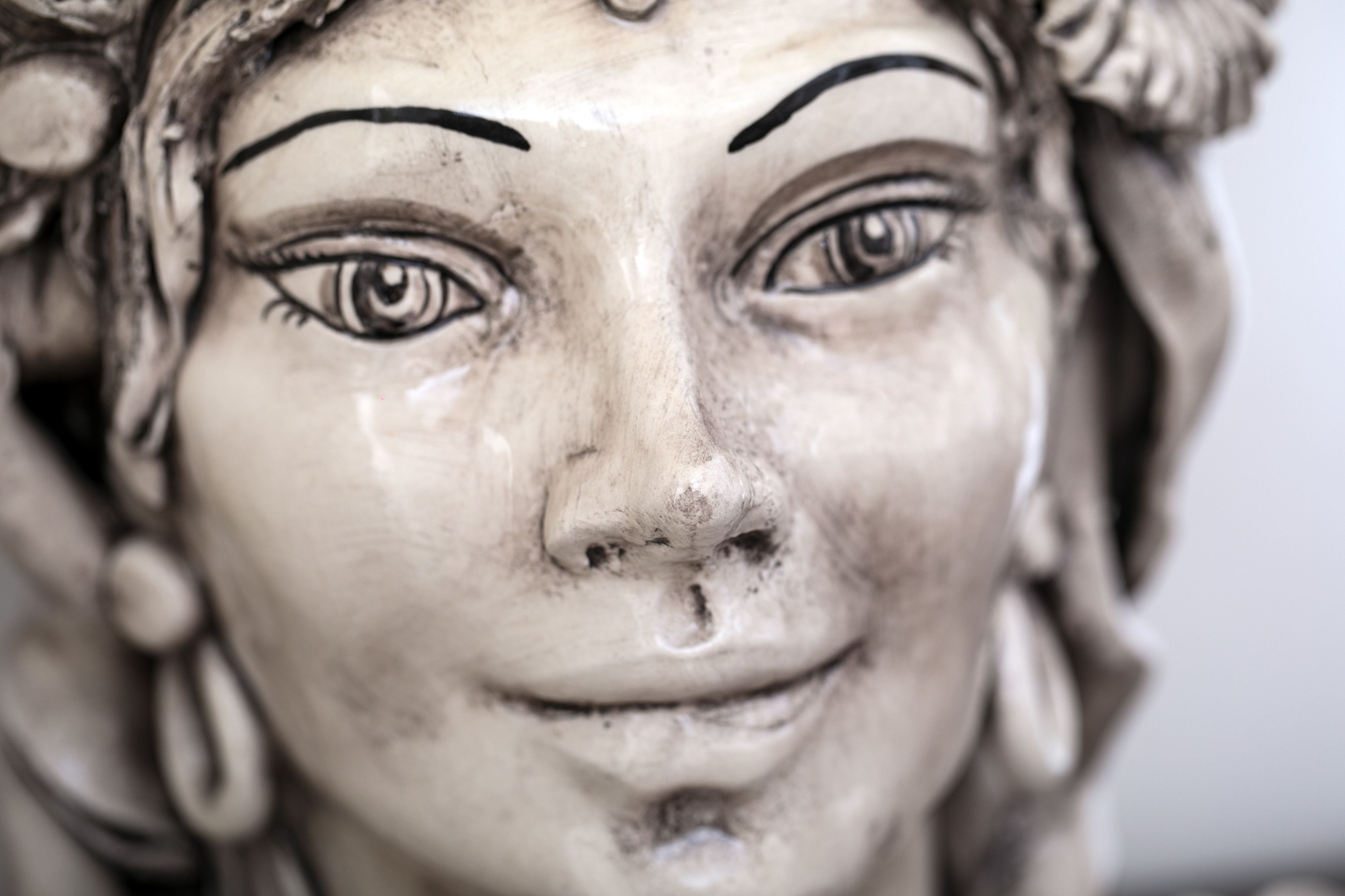 A close-up of a sculpture with detailed facial features and a textured surface.