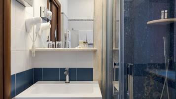 A bathroom with a white sink, a glass-enclosed shower, and a towel rack with a towel.