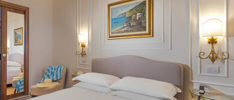 Habitación de hotel con cama, un cuadro, apliques de pared, un espejo y una mesita de noche.