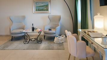 A room with two armchairs, a glass table, a lamp, a desk with a lamp, and a painting on the wall.