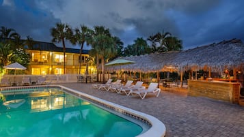 Una piscina al aire libre, sombrillas, sillones reclinables de piscina