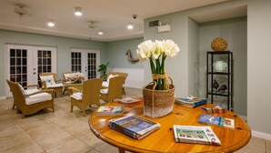 A spacious dining area with wicker chairs, a wooden table, and a vase of flowers. - Naples Garden Inn (Naples)