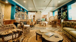 Un rincón lounge acogedor con mobiliario de mimbre, un sofá cómodo y una estantería llena de libros.