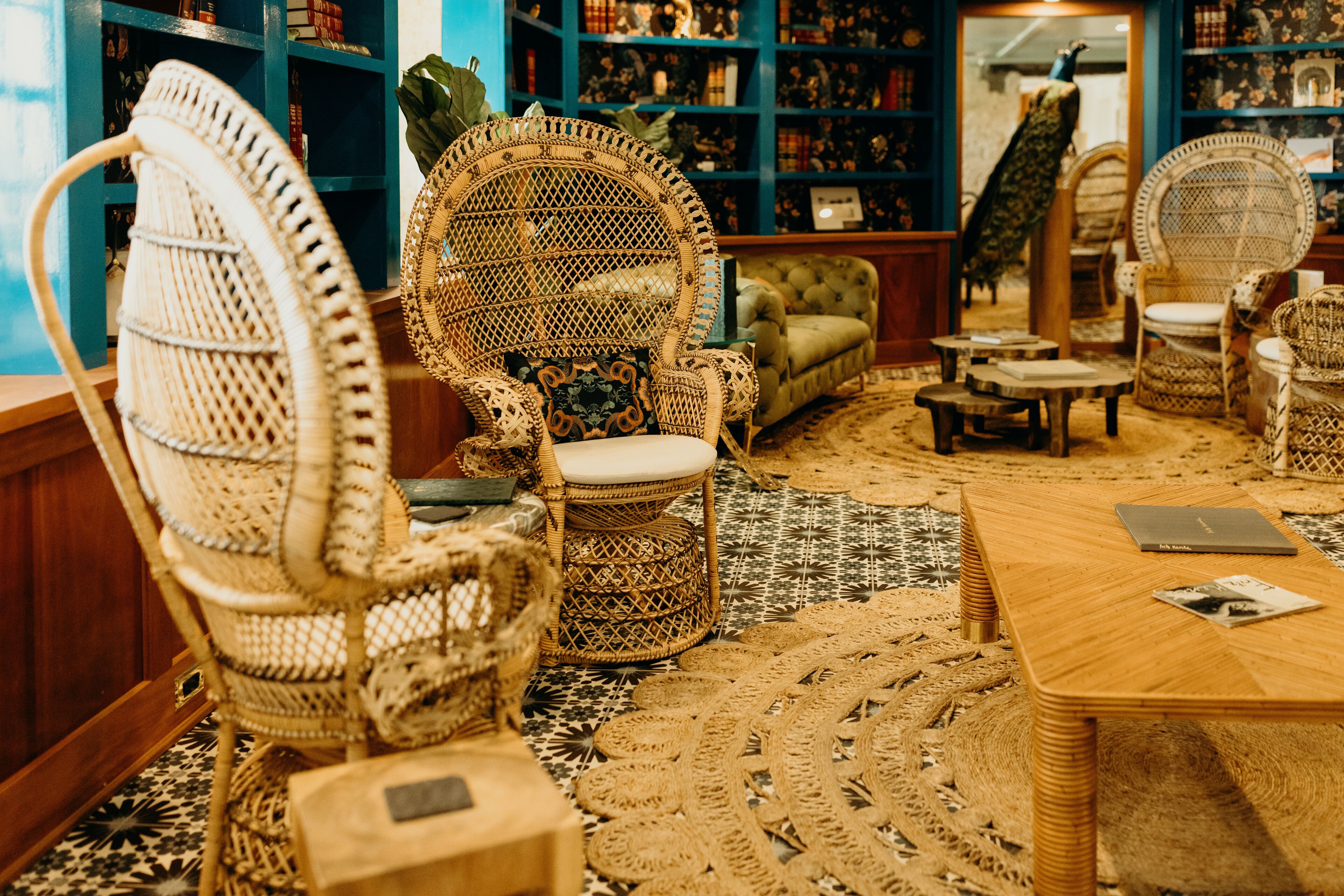 A room with wicker chairs, a wooden table, and a patterned rug.