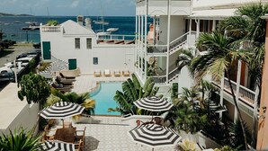 Un resort con piscina, sillas de descanso, sombrillas y vistas al mar.