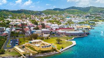 A coastal town with colorful buildings, a marina with boats, and a prominent yellow building with a courtyard.
