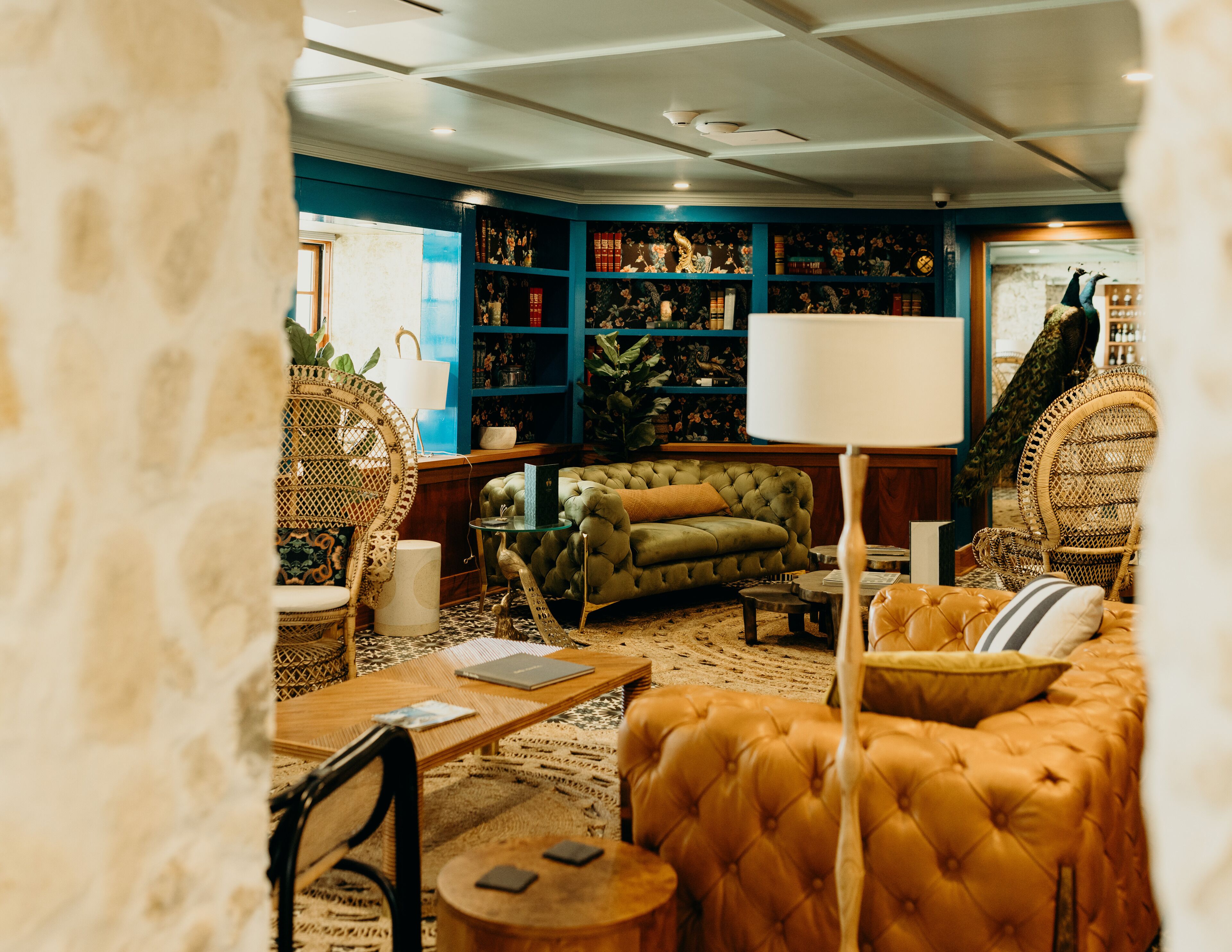 A cozy living room with a green sofa, a brown sofa, a wicker chair, and a lamp.