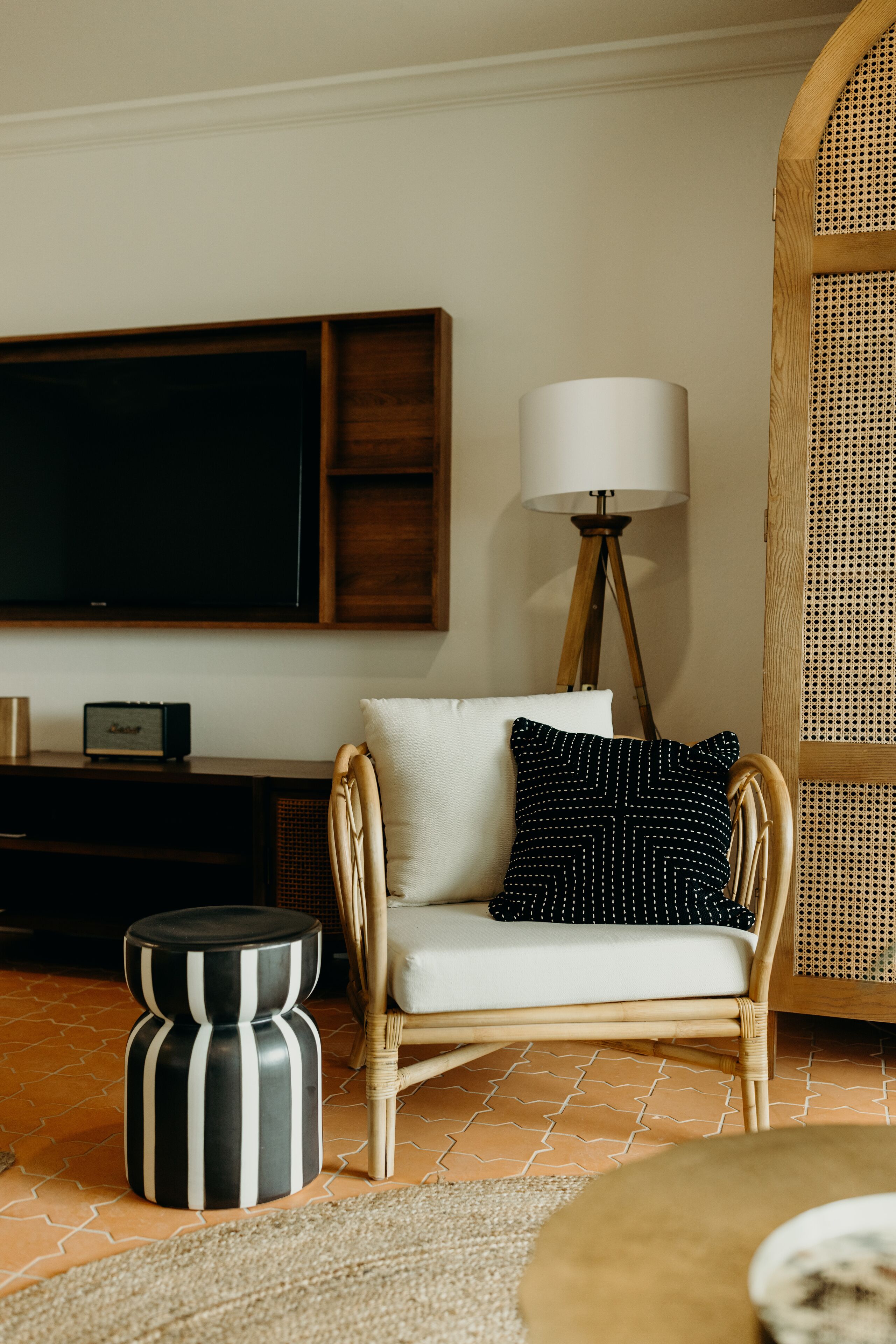 A living room with a television, a lamp, a sofa, and a rattan chair.