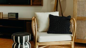 A living room with a television, a lamp, a sofa, and a rattan chair.