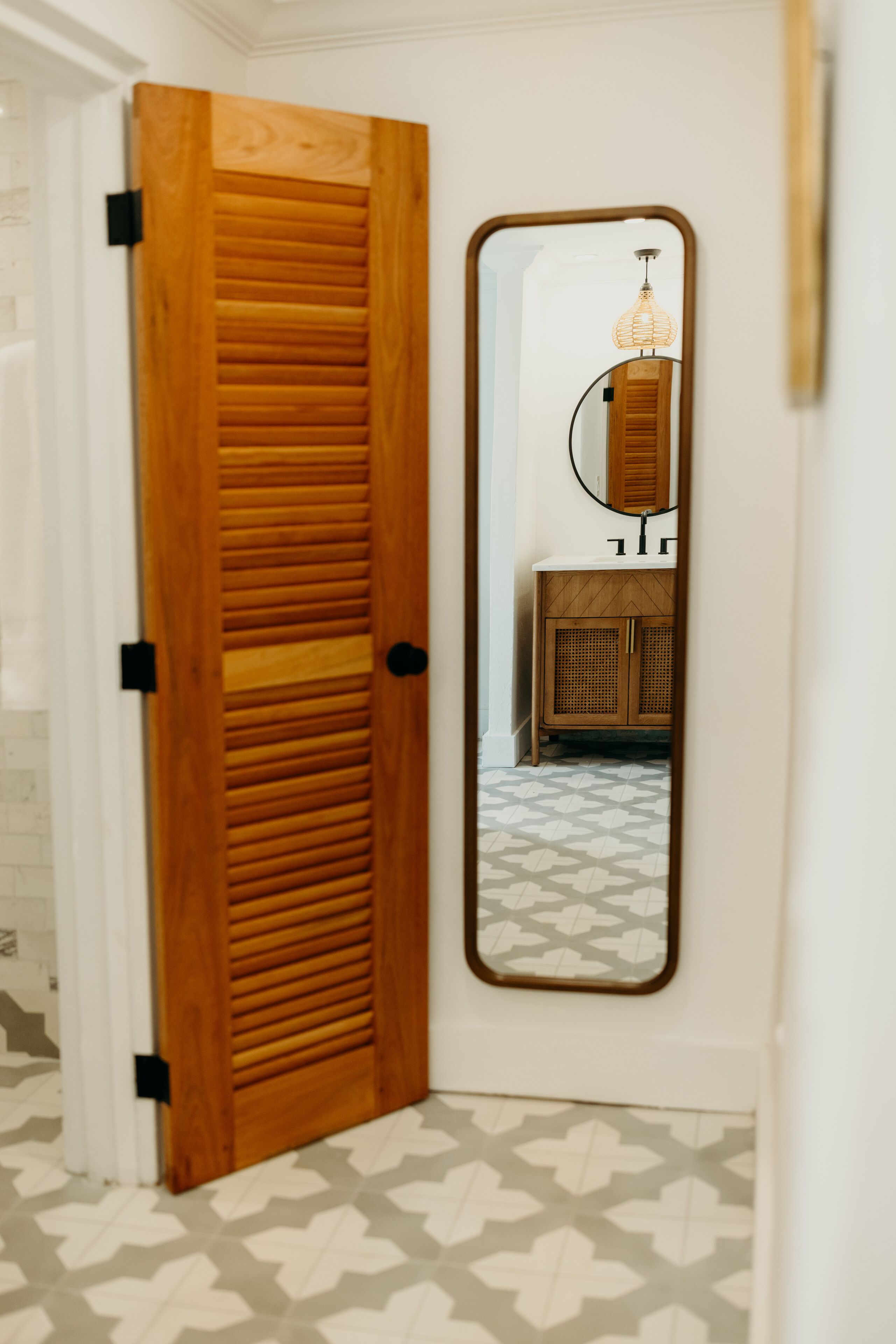 A wooden door with a mirror reflecting a bathroom vanity and a hanging light fixture.