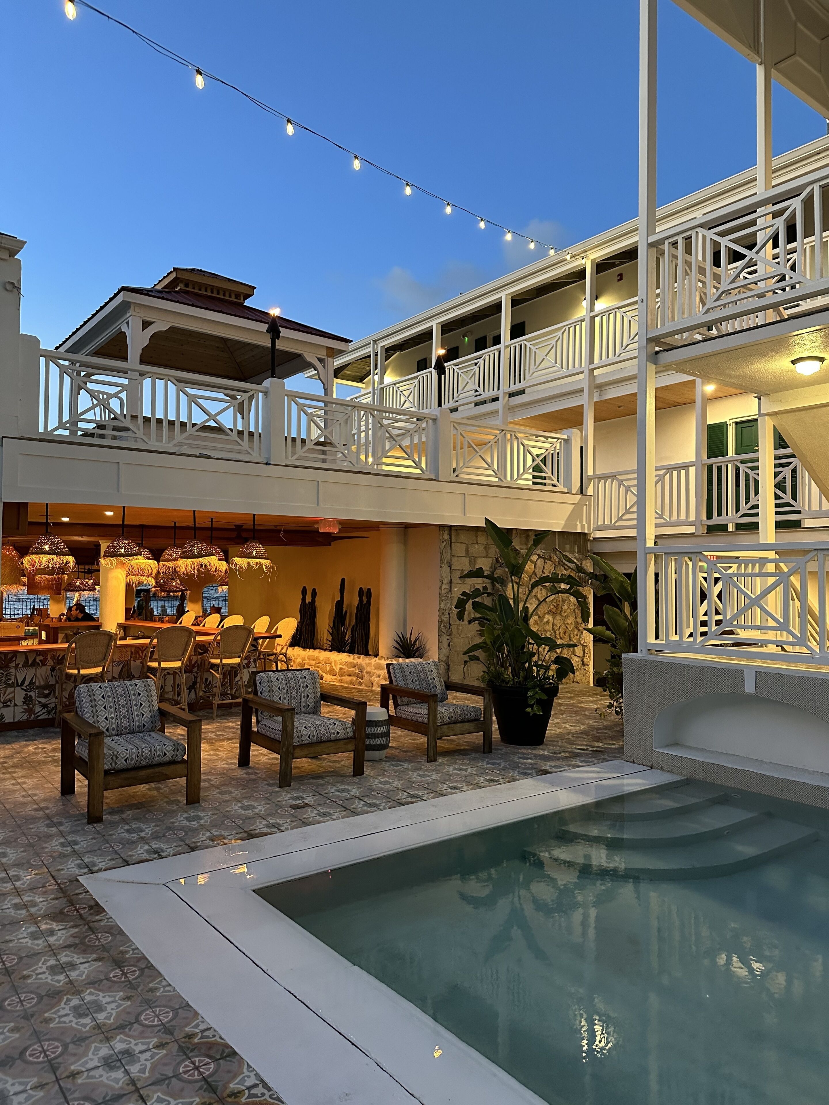 A poolside area with outdoor seating and a bar, surrounded by a multi-level building with balconies.