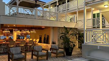 A poolside area with outdoor seating and a bar, surrounded by a multi-level building with balconies.